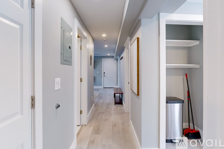 A clean, empty hallway with a trash bin and a vacuum cleaner.