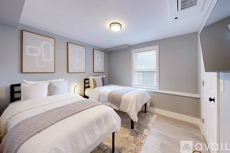 Two beds in a room with white bedspreads and grey headboards.