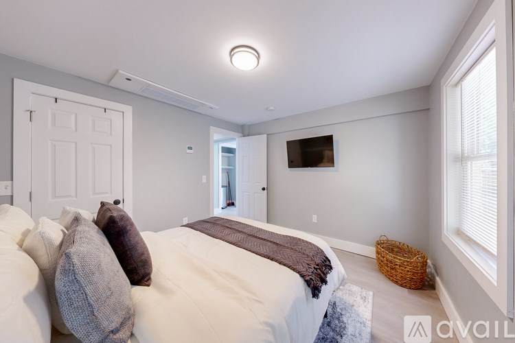 A bedroom with a bed, pillows, and a basket on the floor.