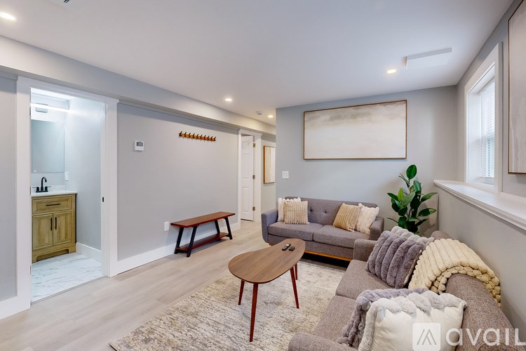 A living room with a grey couch, a wooden coffee table, and a painting on the wall.