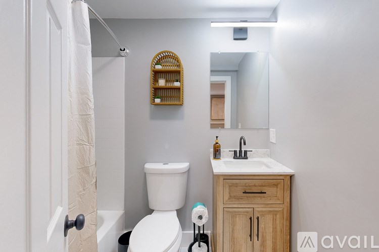 A bathroom with a toilet, sink, and mirror.
