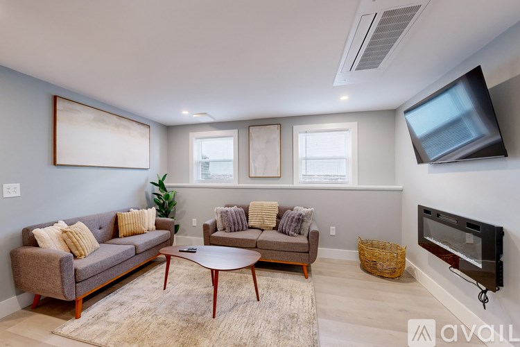 A living room with a grey couch, a brown coffee table, and a flat screen TV mounted on the wall.