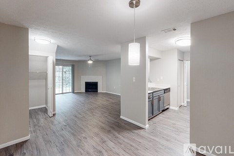 A spacious living room with a fireplace and a kitchen area in the background.