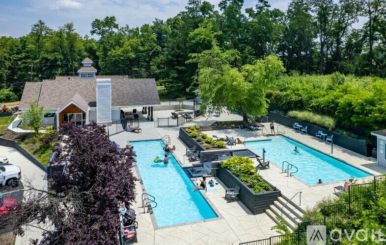 A pool surrounded by trees and a building in the background.