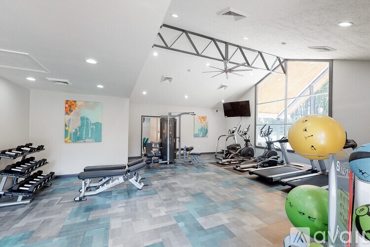 A gym with a variety of equipment including weights, treadmills, and exercise balls.