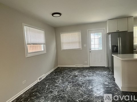 A kitchen with a black marble floor and white walls.