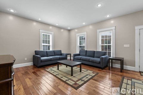 A living room with two grey couches and a wooden floor.