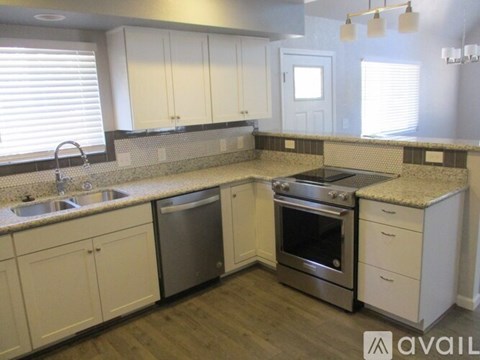 A kitchen with white cabinets and a granite countertop.