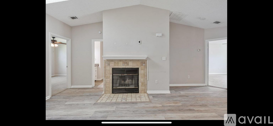 A large, empty living room with a fireplace and a "for sale" sign.