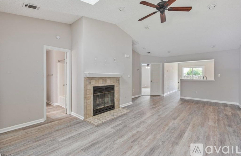 A spacious living room with a fireplace and a ceiling fan.