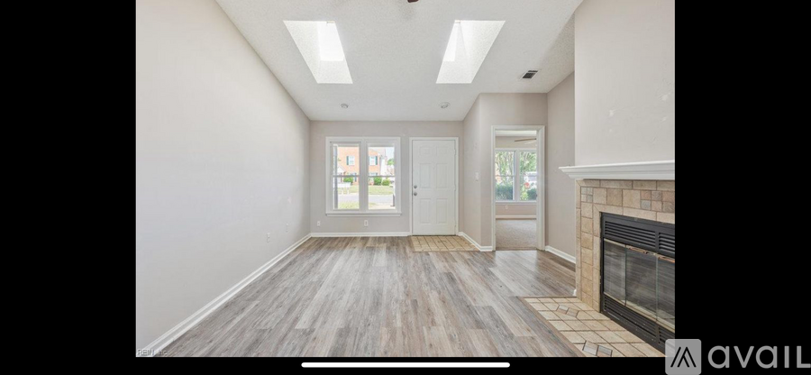 A spacious room with a fireplace and wooden flooring.