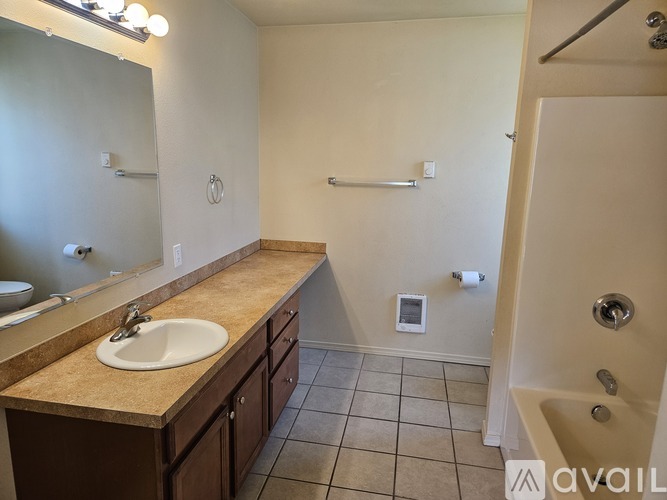 A kitchen area with a white refrigerator, sink, and cabinets.