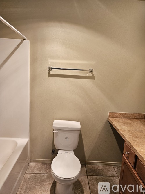 A white toilet in a bathroom with a towel bar above it.