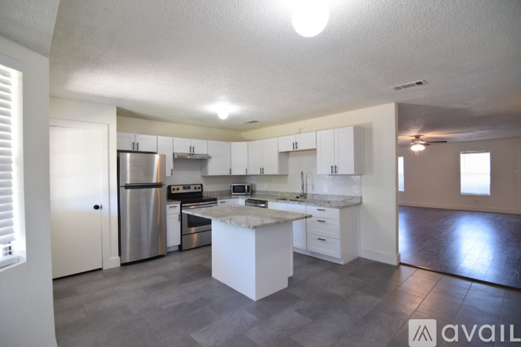 A spacious room with a ceiling fan and a flat screen TV.