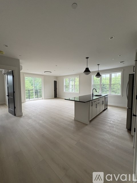 A modern kitchen with a large island and pendant lights.