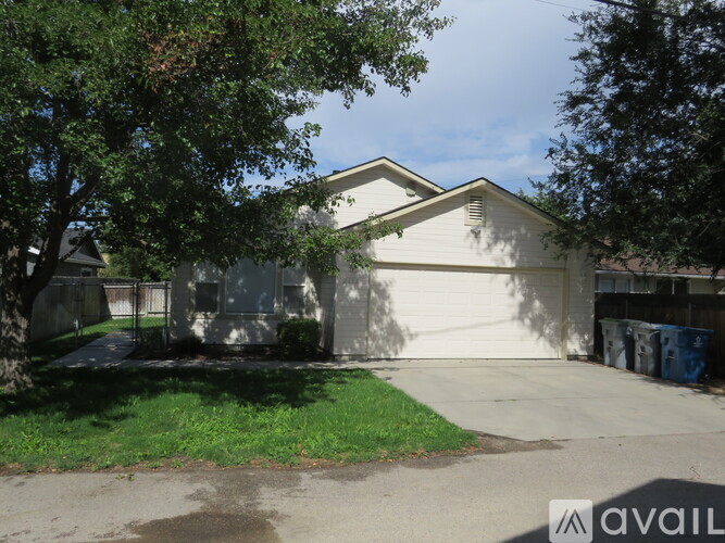 A house with a garage and a tree in front.