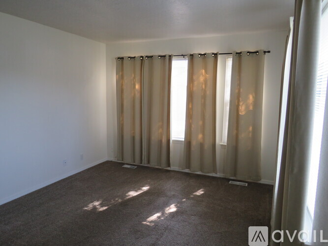 A room with a carpeted floor and a window with curtains.
