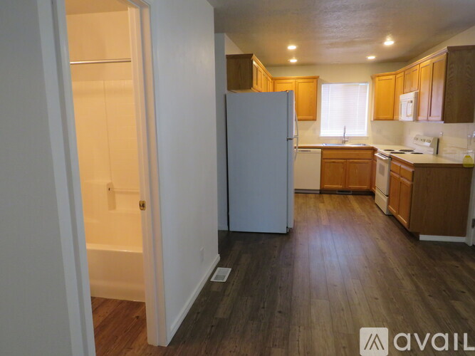 A kitchen with wooden floors and white appliances.