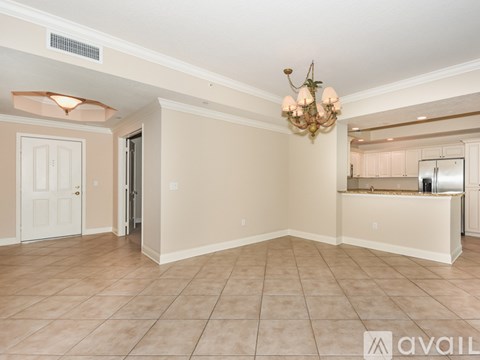 A spacious room with a chandelier and a kitchen in the background.
