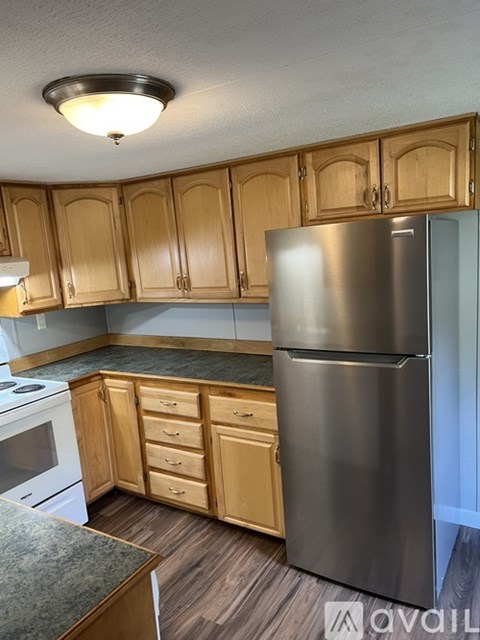 A kitchen with wooden cabinets and a stainless steel refrigerator.