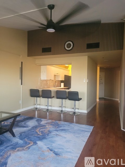 A living room with a blue rug and a ceiling fan.