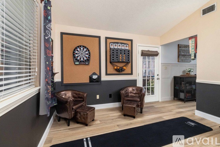 A living room with a dartboard on the wall and two chairs.