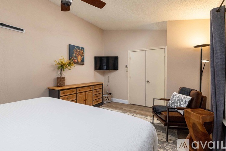 A bedroom with a bed, chair, and a TV.