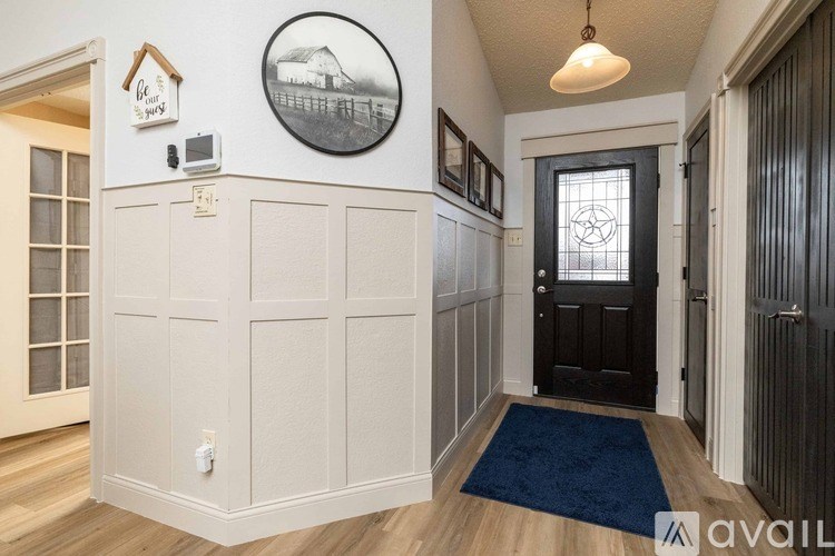A hallway with a black door and a blue rug on the floor.