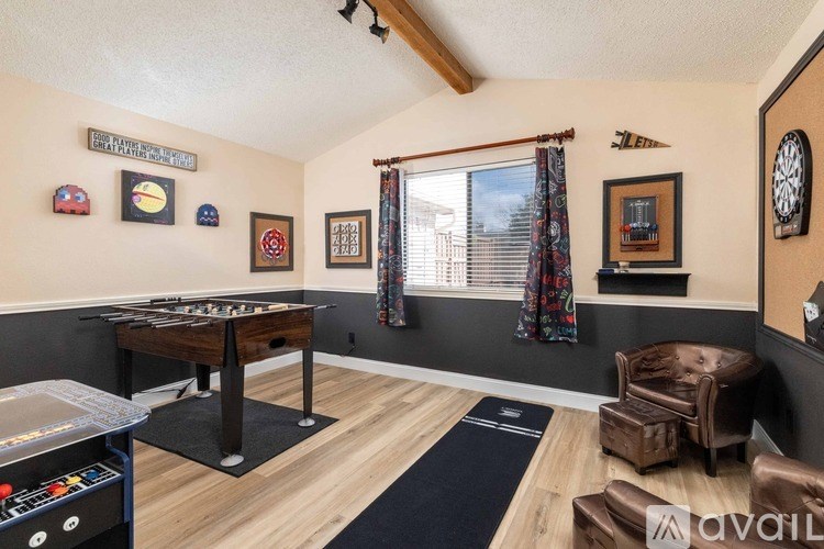 A room with a foosball table, a chair, and a shelf with a clock on it.