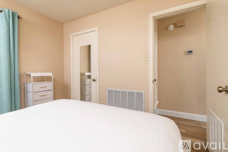 A bedroom with a white bed and a blue curtain.
