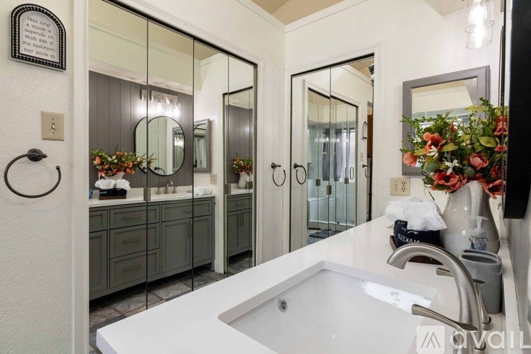 A bathroom with a white tub and a mirror above it.
