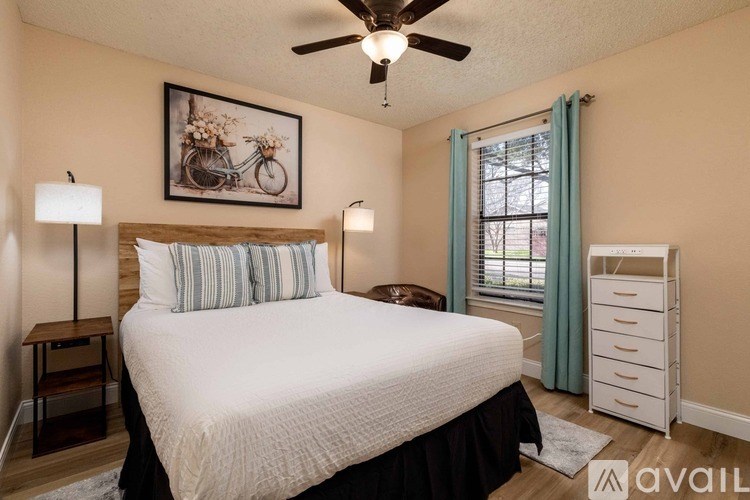 A bedroom with a large bed, a ceiling fan, and a picture of a bicycle on the wall.