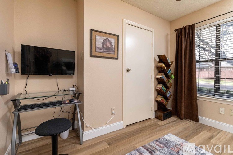 A room with a glass desk and a black stool.