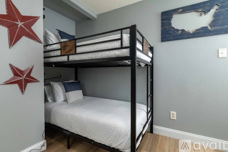 A bunk bed with a white mattress and a white pillow is in a room with a red star on the wall.