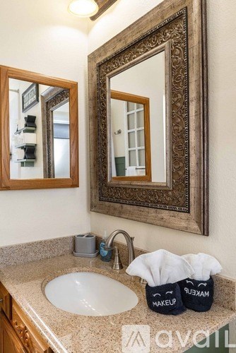 A bathroom with a sink, mirror, and two makeup bags.