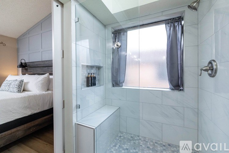 A bathroom with a walk-in shower and a bedroom area.