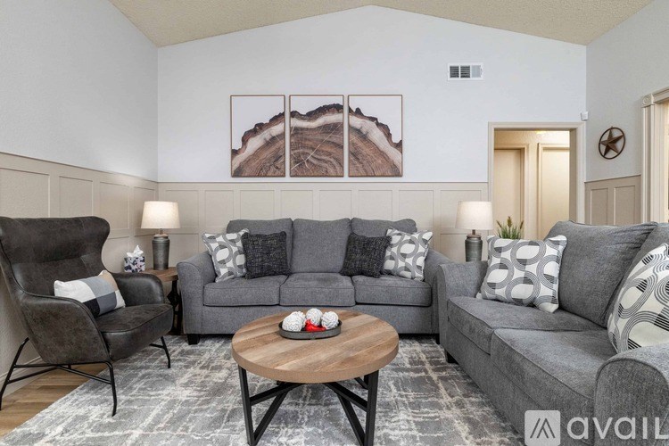 A living room with a grey couch, a chair, a coffee table, and a painting on the wall.