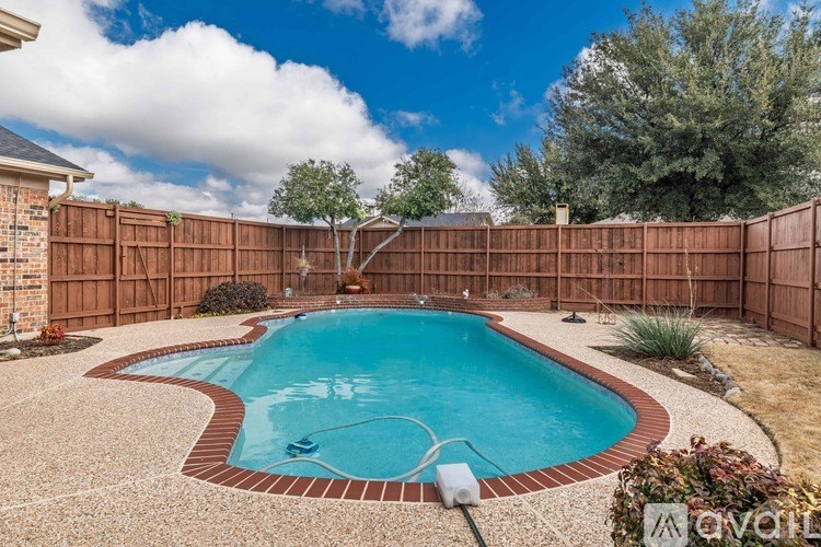 A small pool surrounded by a brick border and a wooden fence.