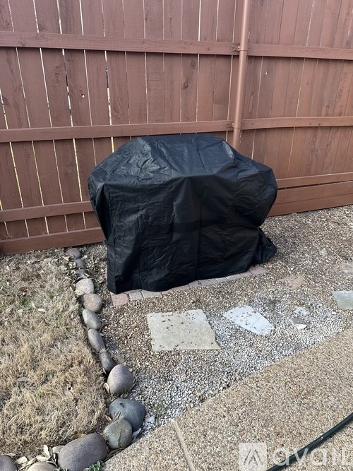 A black tarp is covering an object in a backyard.