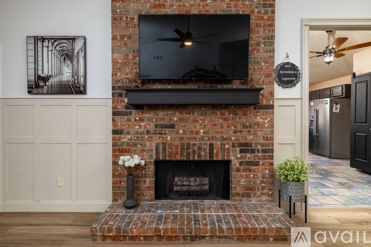 A fireplace with a TV above it and a plant to the side.