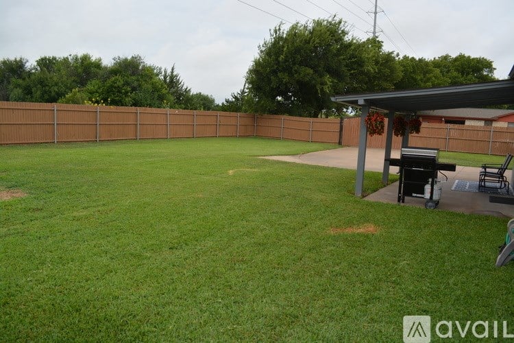 A backyard with a fence and a covered patio area.