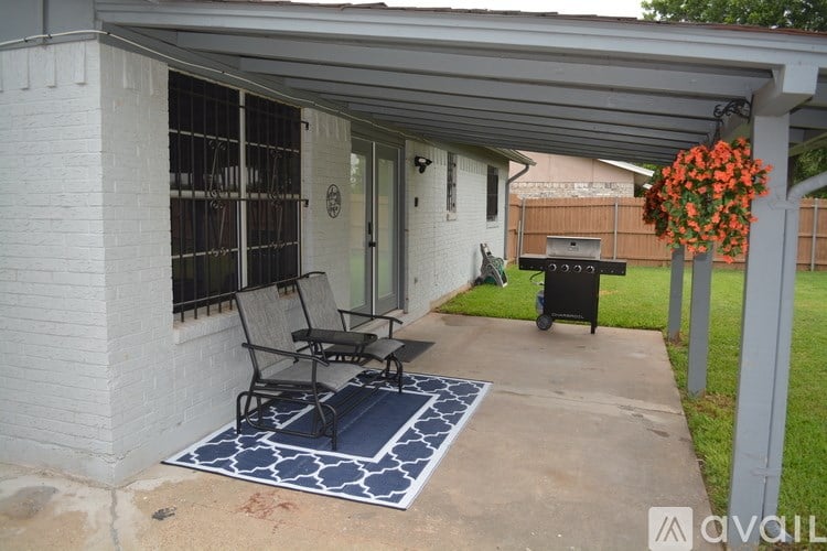 A patio with a black and white rug, a chair and a table.