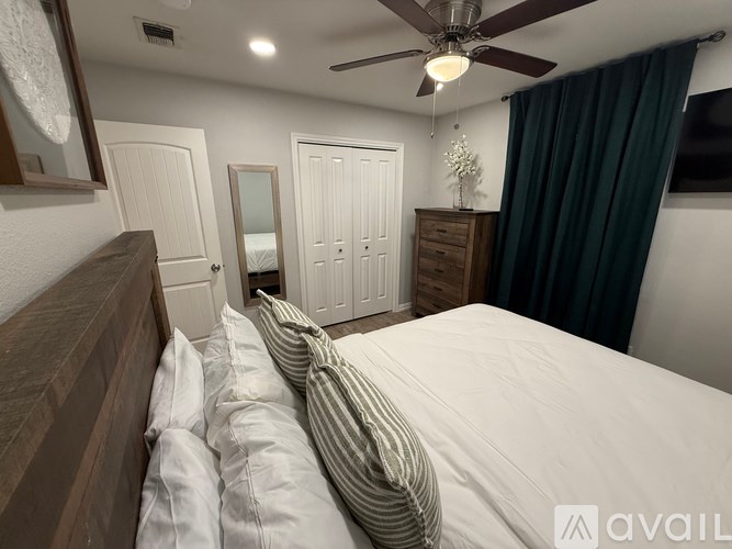 A bedroom with a large bed and a ceiling fan.