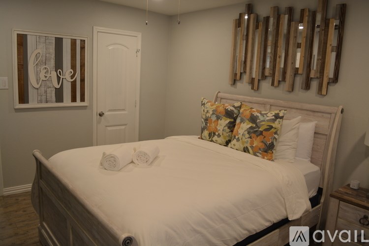 A bedroom with a white bed and a mirror with wooden frames.