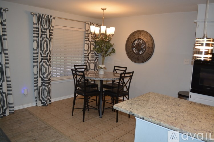A dining room with a table set for two and a chandelier.