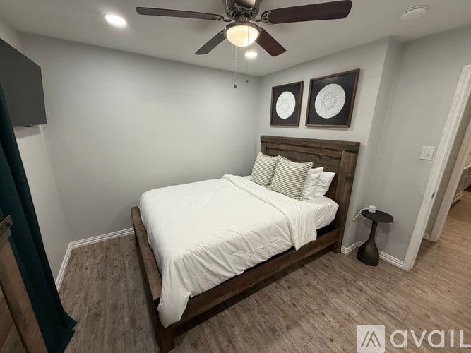 A bedroom with a bed, a ceiling fan, and two wall decorations.