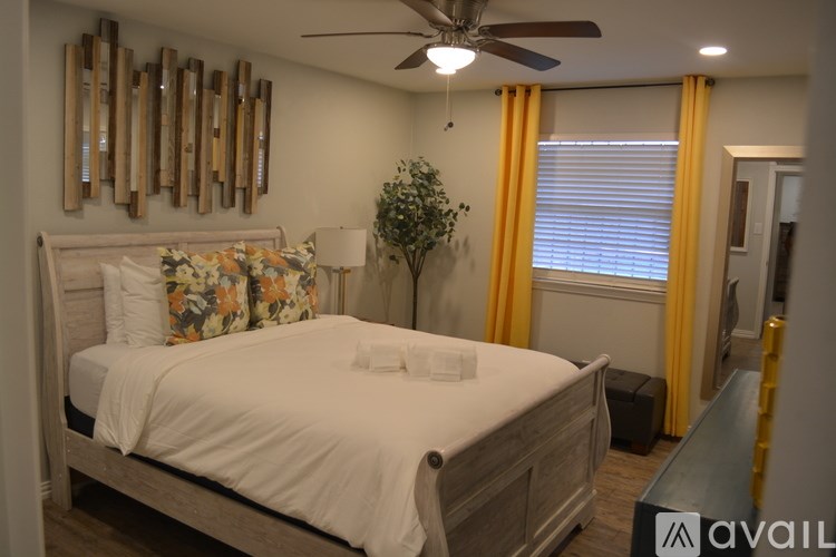 A bedroom with a bed, a ceiling fan, and a mirror on the wall.