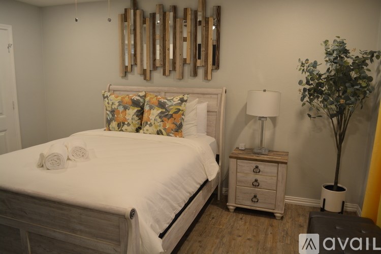 A bedroom with a bed, nightstand, and a plant.