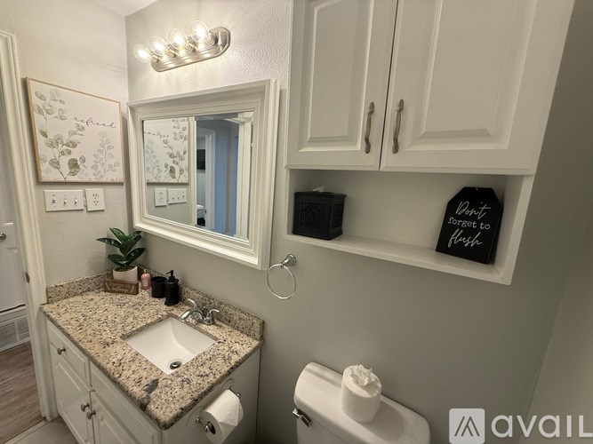 A bathroom with a granite countertop and a mirror above it.