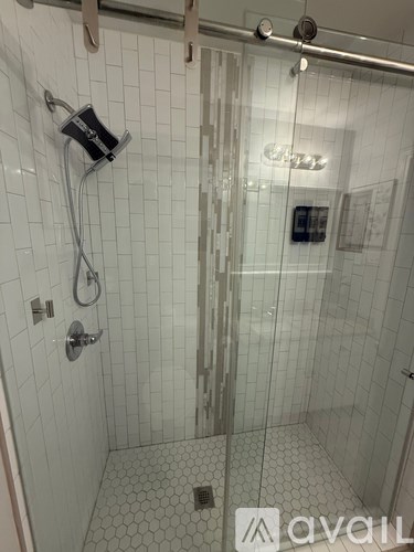 A white tiled bathroom with a glass shower door.